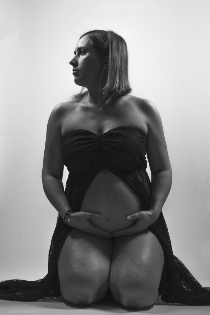 Photo femme enceinte à genoux en noir et blanc