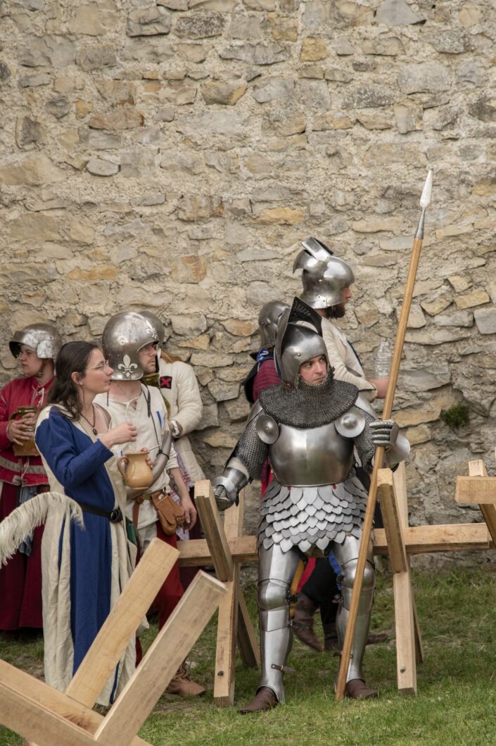 Photo med chevalier tenant une lance avec d'autre personnes vêtus de robe ou vêtements ancien