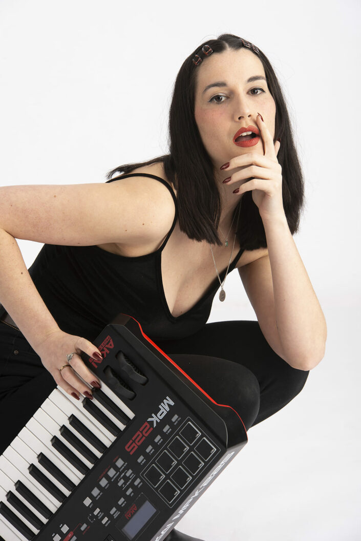 Photo femme assise, habillée en noir avec un piano synthé.